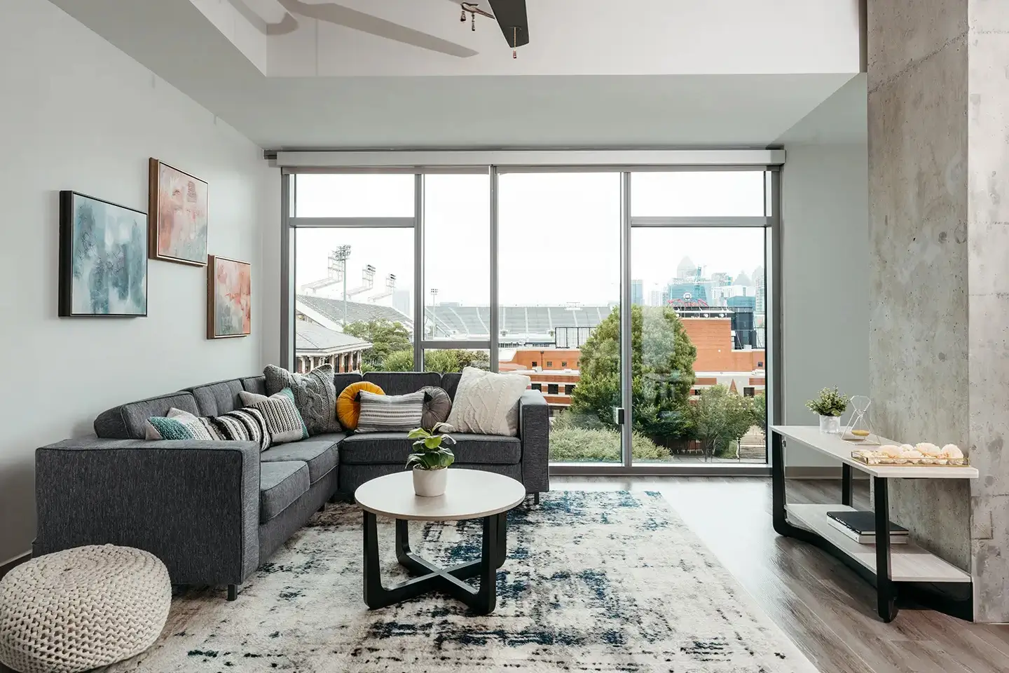 Apartment living room with a rug, couch, coffee table, and large floor-to-ceiling window.